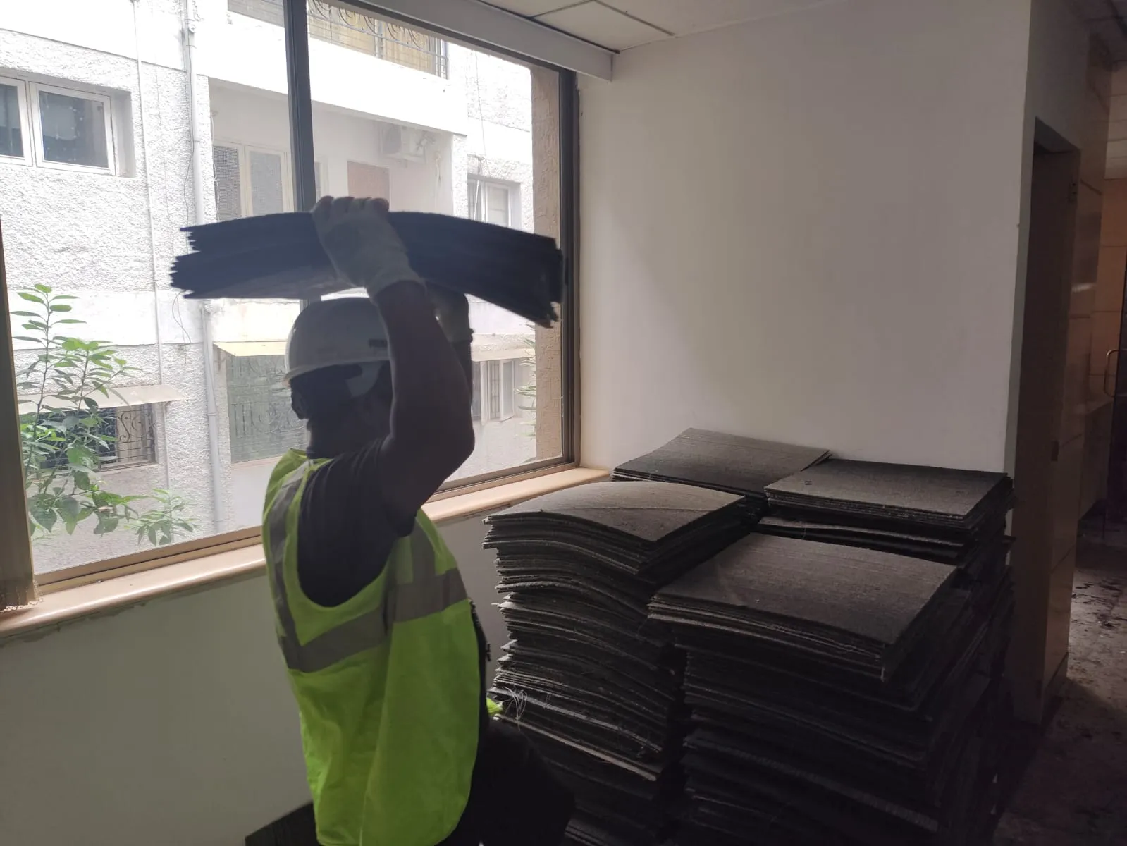 Professional deconstruction worker lifting and stacking modular floor panels during an office dismantling service in Bangalore.